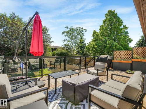 Spacious outdoor deck featuring wood flooring, clear glass panel railings, and built-in lattice planters - 2035 49A Street, Edmonton, AB 