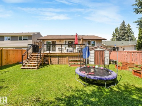 Expansive backyard featuring a manicured lawn, a large wood deck with glass railing, and a multi-level wood staircase - 2035 49A Street, Edmonton, AB 