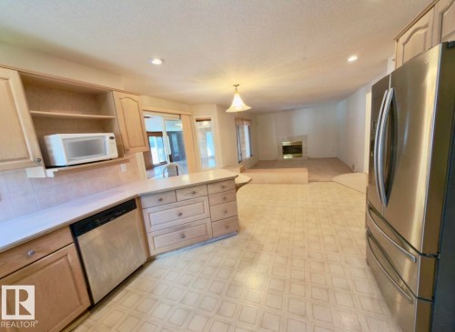 Kitchen featuring wood-finish cabinetry, light-toned countertops, and a built-in dishwasher - 134 Wolf Ridge Place, Edmonton, AB 