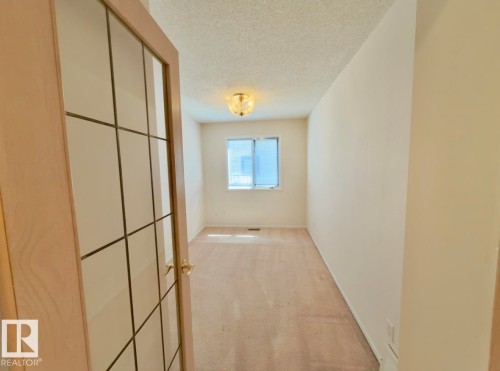 Interior room featuring neutral wall paint, light-colored carpeting, a window with blinds, and a decorative ceiling light fixture - 134 Wolf Ridge Place, Edmonton, AB 
