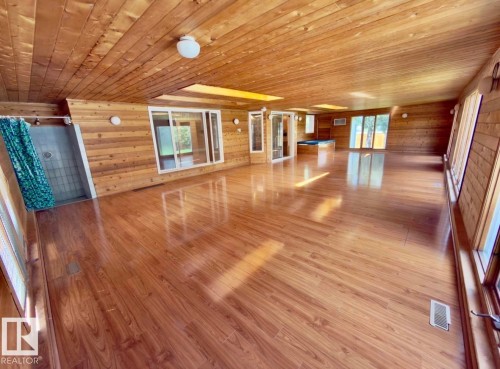 Spacious room featuring wood-finish flooring, wood-paneled walls, and a wood-paneled ceiling - 134 Wolf Ridge Place, Edmonton, AB 
