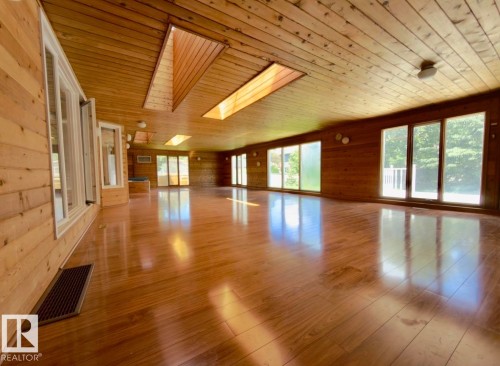 Spacious room featuring wood-finish flooring, wood plank walls, and a wood plank ceiling - 134 Wolf Ridge Place, Edmonton, AB 