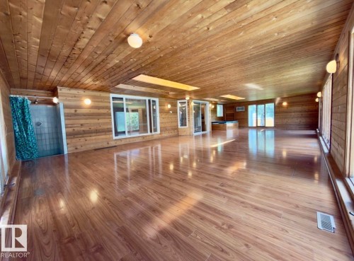 Expansive room featuring wood-finish flooring, wood-paneled walls, and a wood-paneled ceiling - 134 Wolf Ridge Place, Edmonton, AB 
