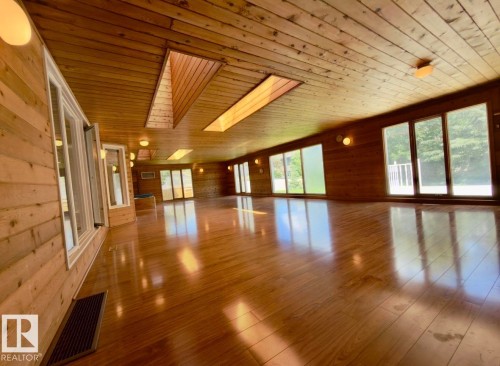 Expansive room featuring wood-finish flooring, wood-paneled walls, and a wood-paneled ceiling - 134 Wolf Ridge Place, Edmonton, AB 