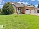 Brick exterior with an arched window accent, featuring a two-car garage with white doors, a gabled roofline, and a paved driveway - 134 Wolf Ridge Place, Edmonton, AB 