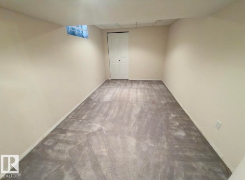 Expansive room featuring light gray carpeting, neutral-toned walls, and white baseboards - 134 Wolf Ridge Place, Edmonton, AB 