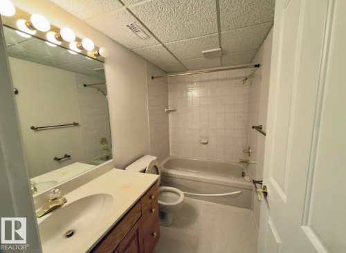 Full bathroom featuring a single vanity with wood cabinetry, a built-in sink, and a light-colored countertop - 134 Wolf Ridge Place, Edmonton, AB 