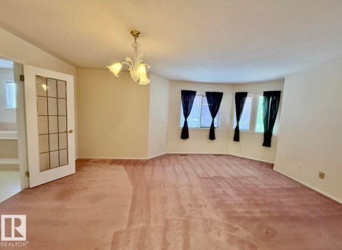 Spacious interior room featuring a bay window, a ceiling-mounted light fixture, and a glass-paneled door - 134 Wolf Ridge Place, Edmonton, AB 