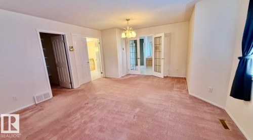 Expansive carpeted room featuring a white ceiling fixture, white walls, and white trim - 134 Wolf Ridge Place, Edmonton, AB 