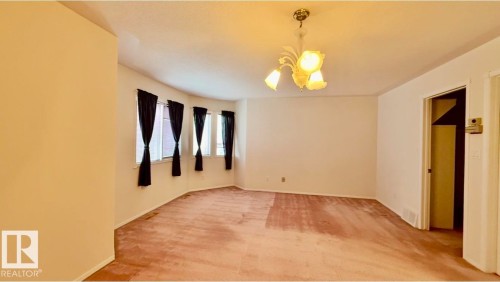 Curved wall featuring multiple windows, a ceiling-mounted light fixture, and light-toned walls - 134 Wolf Ridge Place, Edmonton, AB 