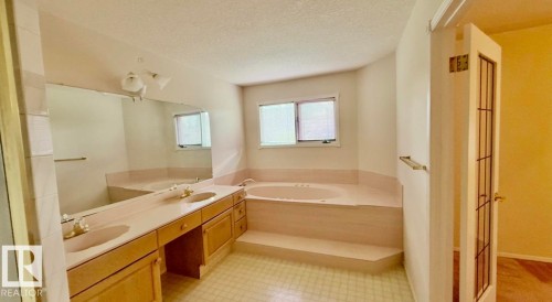 Bathroom featuring a double vanity with light wood cabinetry, dual sinks, and a large wall-mounted mirror - 134 Wolf Ridge Place, Edmonton, AB 