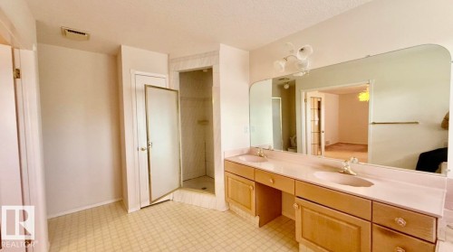 Dual vanity with integrated sinks, light wood-finish cabinetry, and a full-width wall mirror - 134 Wolf Ridge Place, Edmonton, AB 