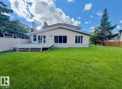 Spacious rear yard with a large deck, white privacy fence, and mature trees - 134 Wolf Ridge Place, Edmonton, AB 