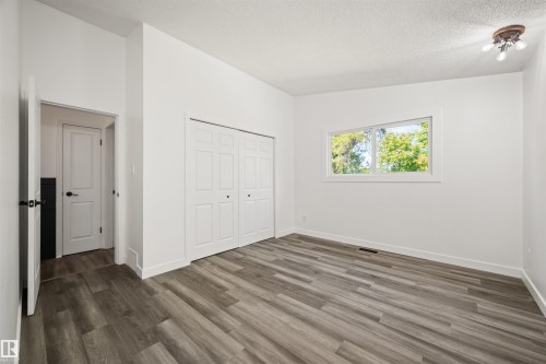 Spacious room featuring wood-finish flooring, white walls, and a large window - 28 Goodridge Drive, St. Albert, AB 