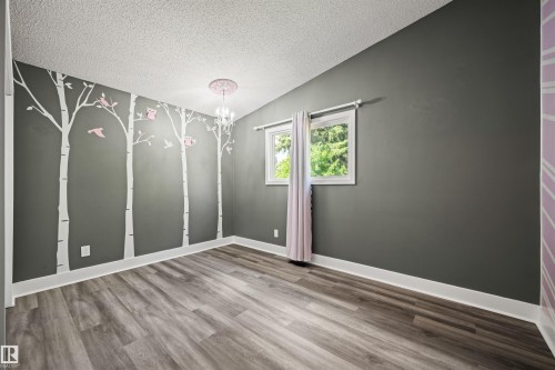 Room featuring wood-finish flooring, two windows with white trim, and a ceiling-mounted chandelier - 28 Goodridge Drive, St. Albert, AB 