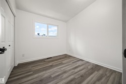 Bright room featuring wood-finish flooring, crisp white walls, and a double-pane window - 