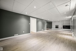 Spacious room featuring wood-finish flooring, recessed lighting, and a white coffered ceiling - 