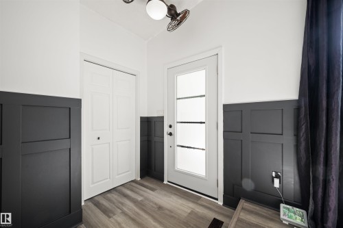 Entryway featuring board and batten wainscoting, wood-finish flooring, and a white paneled door with frosted glass inserts - 28 Goodridge Drive, St. Albert, AB 