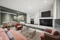 Spacious entertainment area featuring a white painted brick fireplace with hearth, recessed lighting, and wood-finish flooring - 