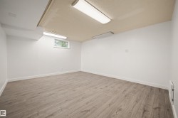 Spacious room featuring light wood-finish flooring, white painted walls, and a textured ceiling with flush-mount lighting fixtures - 