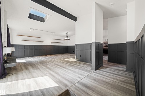 Spacious room featuring wood-finish flooring, wainscoting, a skylight, exposed beam, and track lighting - 28 Goodridge Drive, St. Albert, AB 