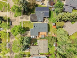 Aerial view showcasing two residential properties featuring mature landscaping, a private wooden deck, and a solar panel system on one roof - 