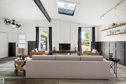Vaulted ceiling with exposed beam, white brick fireplace with dark tile hearth, and wood-finish flooring - 28 Goodridge Drive, St. Albert, AB 
