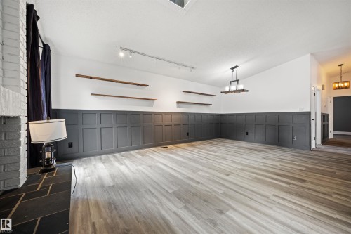 Spacious interior featuring wide plank wood-finish flooring, wainscoting paneling, and a vaulted ceiling - 28 Goodridge Drive, St. Albert, AB 