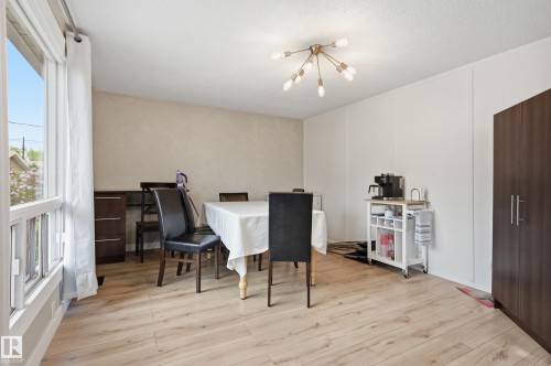 Spacious interior with wood-finish flooring, a contemporary ceiling light fixture, and large window with vertical mullions - 12326 92 Street, Edmonton, AB - Indoor