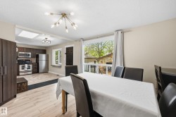 Bright dining area featuring wood-finish flooring, a contemporary ceiling light fixture, and a large window - 