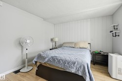 Bedroom featuring light wood-finish flooring, white vertical plank accent wall, and textured white ceiling - 