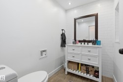 White subway tile accent wall with a dark wood-framed mirror - 