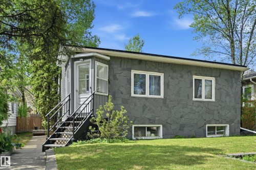 Property exterior featuring a gray stone facade, white trim windows, and a raised entry with black metal railings - 12326 92 Street, Edmonton, AB - Outdoor
