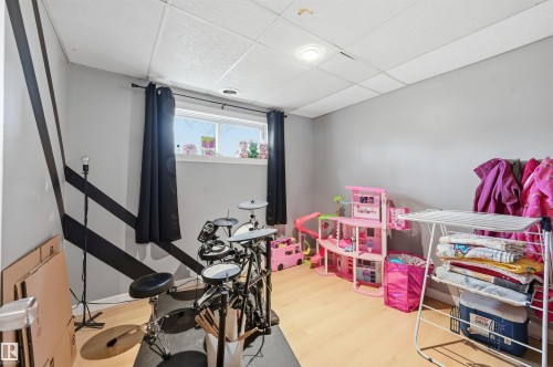 Room featuring wood-finish flooring, a drop ceiling with recessed lighting, and grey walls with a black geometric accent - 12326 92 Street, Edmonton, AB - Indoor