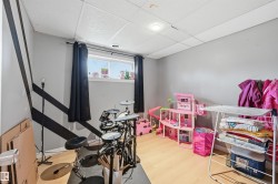 Room featuring wood-finish flooring, a drop ceiling with recessed lighting, and grey walls with a black geometric accent - 
