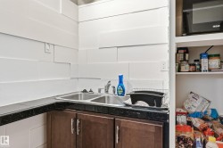 Compact kitchen area featuring a double-basin stainless steel sink, dark speckled countertop, and wood-finish lower cabinetry - 