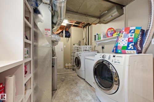 Dedicated utility area featuring a washer and dryer, exposed ductwork, concrete flooring, and built-in shelving - 12326 92 Street, Edmonton, AB - Indoor Photo Showing Laundry Room