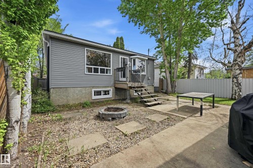 Backyard featuring a concrete patio, stone fire pit, and mature trees - 12326 92 Street, Edmonton, AB - Outdoor