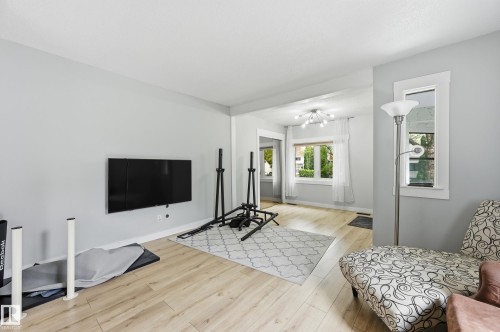 Light wood-finish flooring extends throughout this open living area - 12326 92 Street, Edmonton, AB - Indoor
