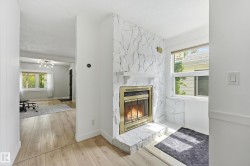 Stone-clad fireplace with a brass-trimmed insert, complemented by light wood-finish flooring - 