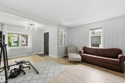 Spacious room featuring light wood-finish flooring, a modern sputnik chandelier, and a dark entry door - 