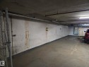 Concrete parking area with a painted concrete floor and overhead utility pipes - 10179 105 St, Edmonton, AB 