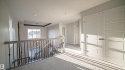 Upper-level hallway with light-toned carpet flooring and paneled doors - 