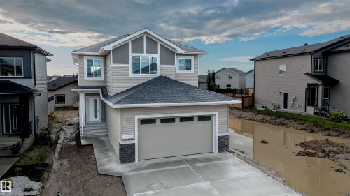 Two-story home with a light beige and dark gray exterior, featuring a double garage and a multi-pane front door - 44 Dalquist Bay, Leduc, AB 