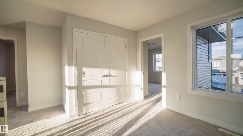 Light gray wall finishes and carpeting throughout, featuring a double-door closet with paneling and white trim - 44 Dalquist Bay, Leduc, AB 