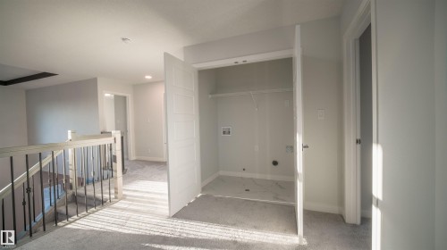 Upper-level hallway featuring a laundry closet with tile flooring and utility connections - 44 Dalquist Bay, Leduc, AB 