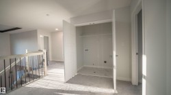 Upper-level hallway featuring a laundry closet with tile flooring and utility connections - 