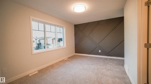 Bedroom featuring a decorative accent wall, neutral carpeting, and a flush mount ceiling light fixture - 44 Dalquist Bay, Leduc, AB 