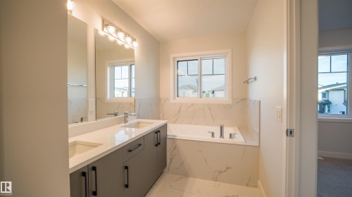 Contemporary bathroom featuring a dual vanity with quartz countertops, integrated sinks, and matte black hardware - 44 Dalquist Bay, Leduc, AB 