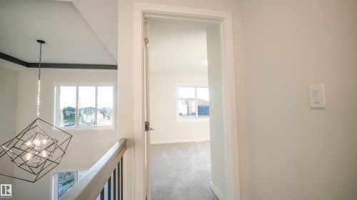 Modern geometric chandelier illuminating a stairwell with dark wood railing and white pickets - 44 Dalquist Bay, Leduc, AB 